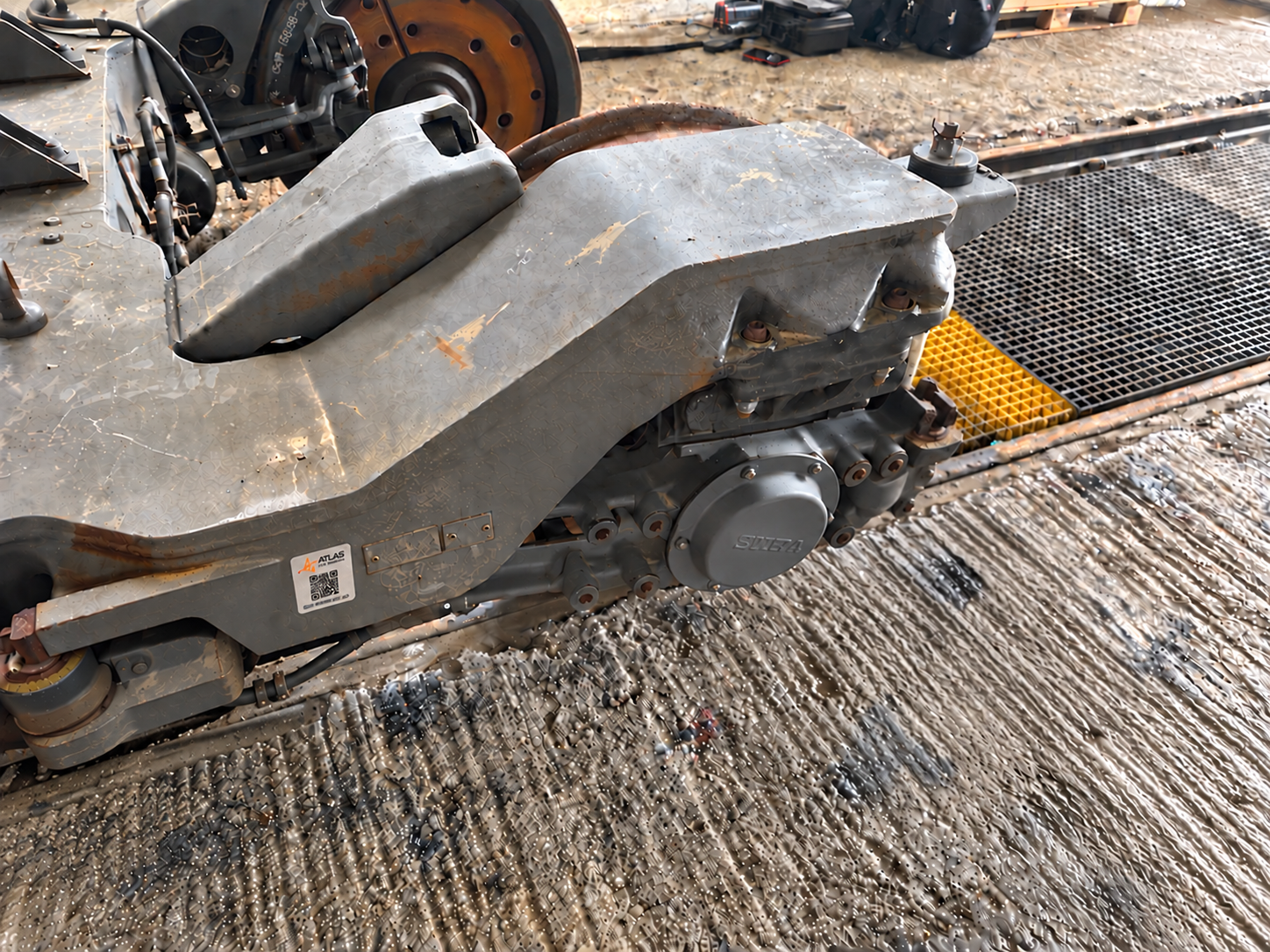 An aluminium ATLAS QR label attached to a trailer bogie frame beside its identification plates.